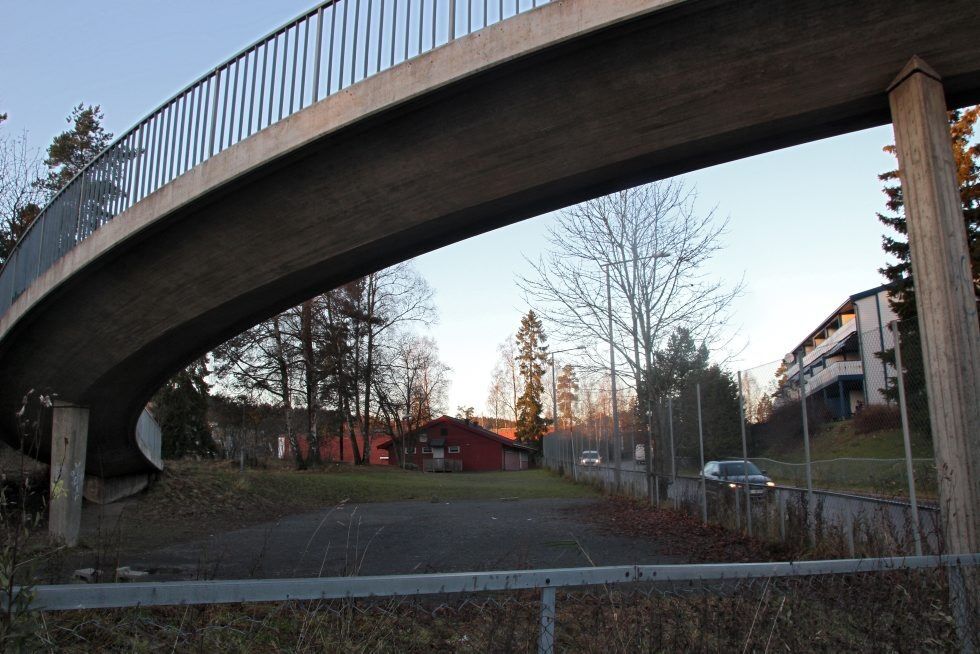 KAN BLI PARKERINGSPLASS: Det lille grusbelagte området som ligger rett bak brua og sør for skolen, ses nå på som et aktuelt området til å få inn flere parkeringsplasser. Foto: