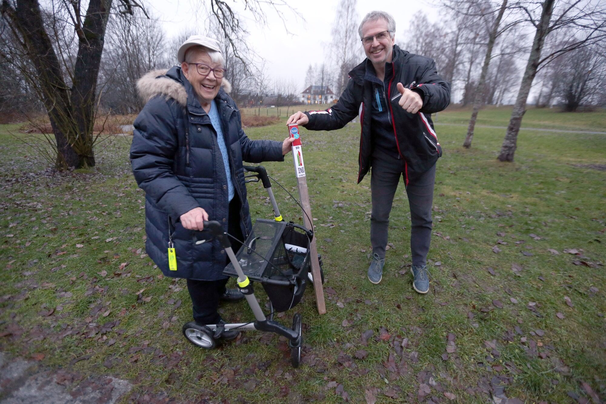 OPPDRAG UTFØRT:Anne-Lise Ruud manglet kun stolpe Nr. 10 i årets stolpejakt. Hun hadde klart 89 av 90, men med rullator nådde hun ikke helt frem til den aller siste. Da tok stolpejaktsjef Vidar Benjaminsen med seg stolpen til henne, slik at hun høyst fortjent oppnådde alle 90 – i en alder av 90! Foto: