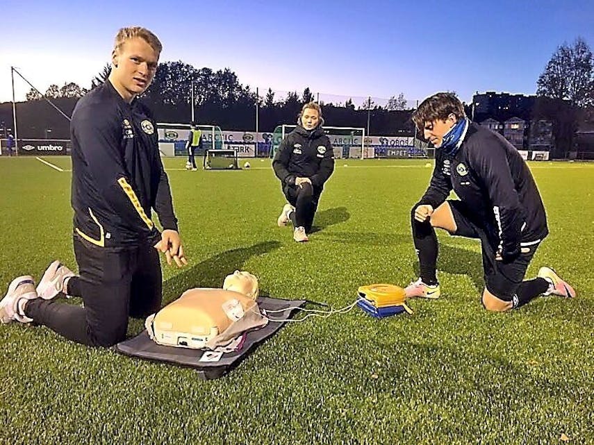 TEST: Grorud-spillerne Geirald Meyer og Vetle Skåttun testet ut klubbens nye hjertestarter sammen med lederen for barnefotballen i klubben, Vilde Mollestad Rislaa. Foto: