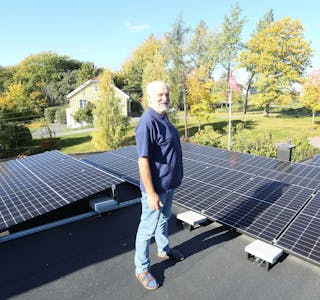SMART TREKK: Ved å legge solcellepaneler på taket kan Tormod Knutson nå selge strøm til kraftleverandører. Inntektene betyr at han kan betale sin egen strømregning og fremdeles sitte igjen med en månedlig gevinst. I bakgrunnen ser vi Grorud prestegård. Foto: Rolf E. Wulff