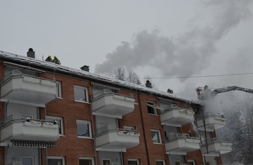 BRANN: Brannvesenet jobber med å slukke brannen som har spredd seg fra en leilighet til taket og oppgangen ved siden av. Foto: