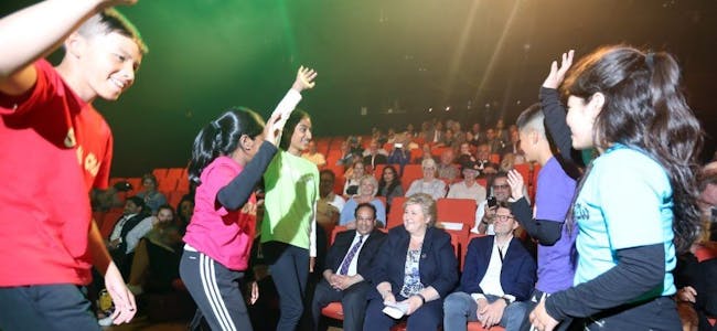 MYE Å VISE FRAM: Da statsminister Erna Solberg (H) besøkte Rommen scene tirsdag kveld la hun trykk på at det er viktig å vise fram alt det positive som skjer. Her lærer hun noen nye dansemoves av Vestli-dansere fra Surreal Crew. Foto: