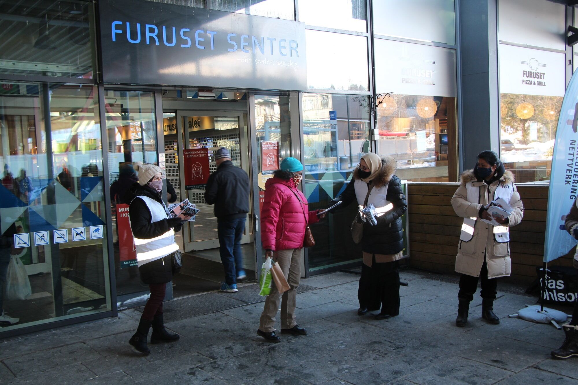 TYDELIG INNSATS: Radhia Sahbi (f.v) og Hasna Laghaide delte ut munnbind og svarte på spørsmål fra forbipasserende. Flere var nysgjerrig på om munnbindet skulle vaskes før bruk og på hvor mange grader. Ved behov vekslet duoen mellom å snakke norsk og arabisk. Foto: