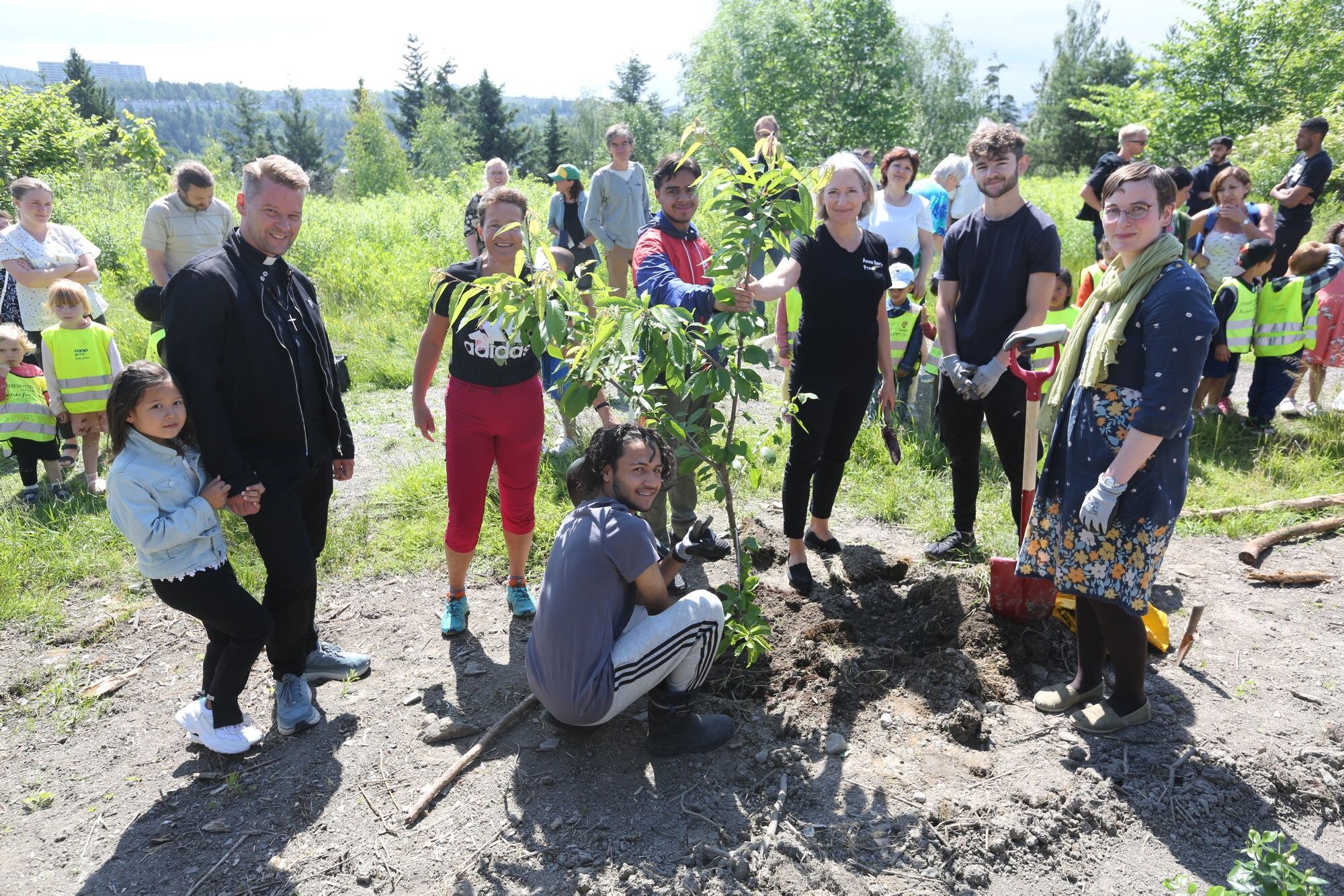 PÅ PLASS:Endelig sto det første frukttreet i jorda i Ulven nærmiljøhage. Prost i Groruddalen Prosti, Øyvind Stabrun (f v), menighetsrådgiver Eli Solberg, sokneprest Anne Berit Evang, prest Sara Moss-Fongen, samt Amir og Mustafa fra de arbeidende ungdommene gleder seg over resultatet. Foto: