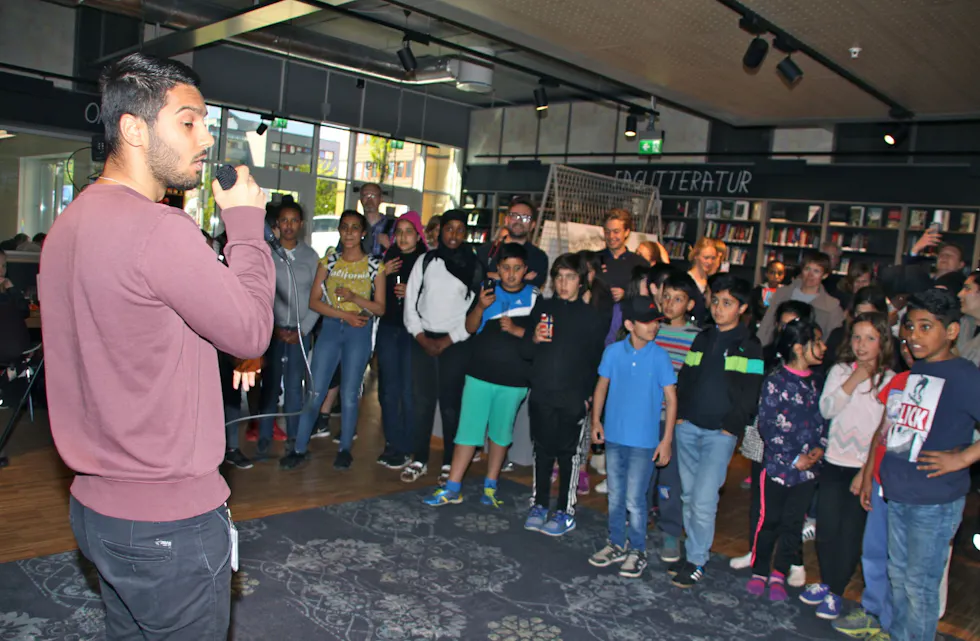 FOLKSOMT: Flere møtte opp på åpningen. Her rapper Temoor Ul Hassan foran publikum. Foto: