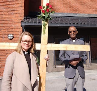 MED KORSET: Sokneprest Elin Lunde og vikarprest Yohannes Shanka foran inngangspartiet til Fossum kirke. Foto: