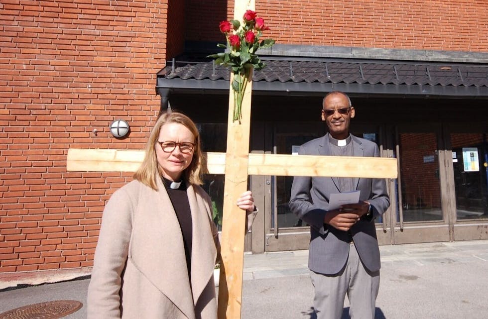 MED KORSET: Sokneprest Elin Lunde og vikarprest Yohannes Shanka foran inngangspartiet til Fossum kirke. Foto: