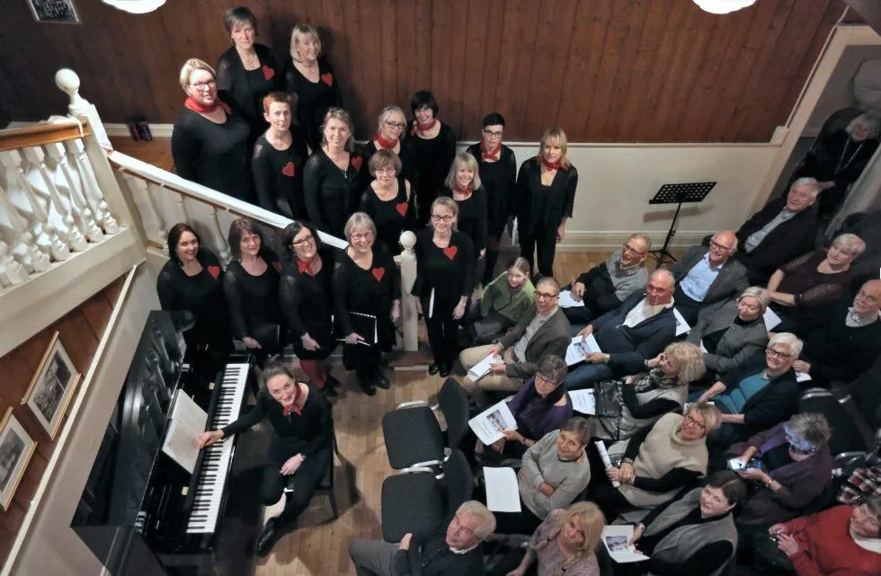 UVANLIG SCENE: Koret Koriander fra Hellerud brukte trappa som scene da de holdt julekonsert i Trosterudvillaen, og det fungerte utmerket. Ved pianoet er korets dirigent Julia Selina Blank. Foto: