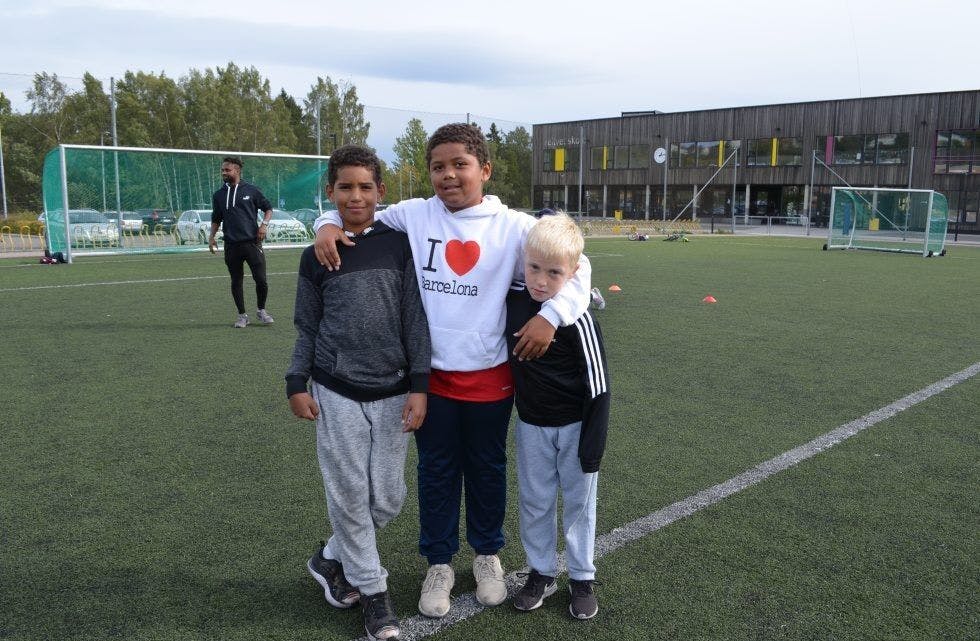 TRIVES: Noah (8 år), Benjamin (9 år) og Noah (8 år) har spilt fotball på Veitvet i mange år og stortrives på kunstgressbanen. Foto: