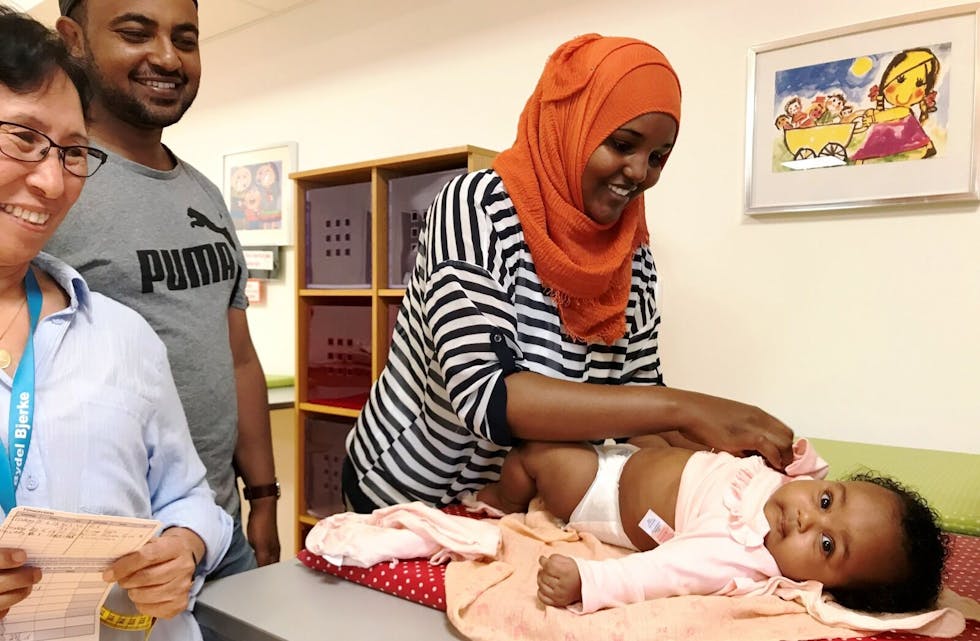 TRYGT OG GODT: – Det er veldig fint her, sier Abshiro Abdi mens hun kler på seks måneder gamle Hawi. Pappa Muhadin Ali er også godt fornøyd med tilbudet som ytes av blant andre barnepleier Nyima Yangchen (t.v.) på helsestasjonen på Veitvet. Foto: