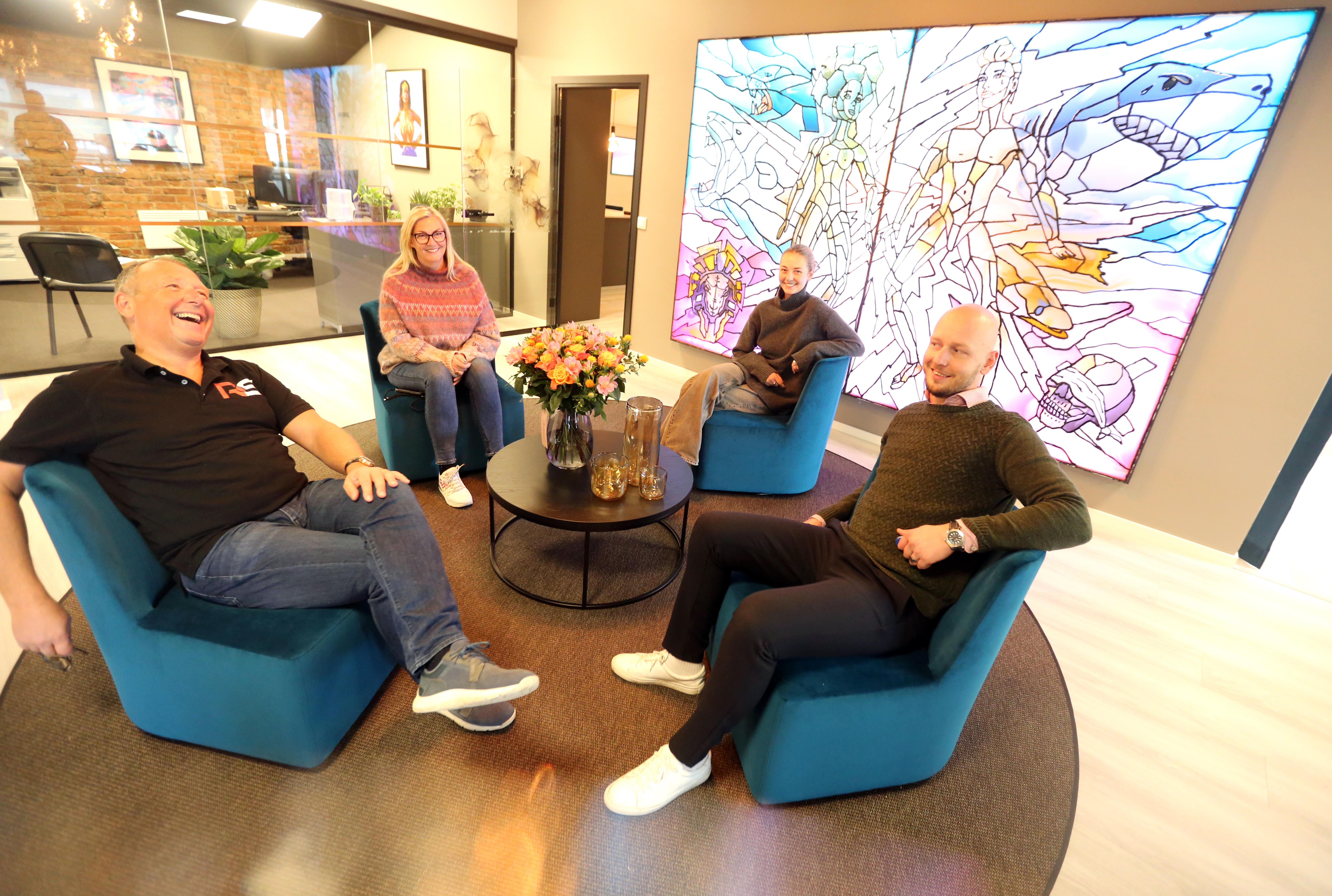 GODT HUMØR: Smilet er alltid på plass hos Rørlegger Sentralen. Innehaver Gunnar André Ludvigsen (f.v.), markedsansvarlig Gry Ludvigsen, regnskaps og markedsføringskoordinator Andrea Ludvigsen og daglig leder Anders Berge slapper av i den koselige resepsjonen med NiX sin lysende mosaikkunst på veggen.