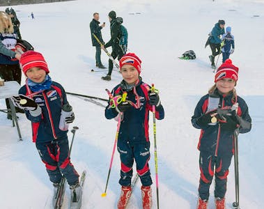 Emil (8), Luca (8) og Nomi (8) viser stolte fram medaljen og beviset på at de fullførte dagens renn. De forteller at skicrossen var en suksess, men at det aller morosmste var å passere så mange i løypa.