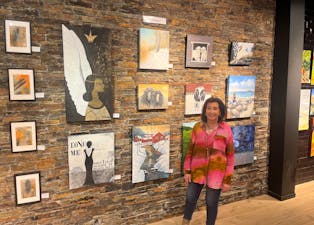Mette Tuen Bakken og hennes malerier i bakgrunn. Hun er glad i å male bilder av dyr og livlig natur.