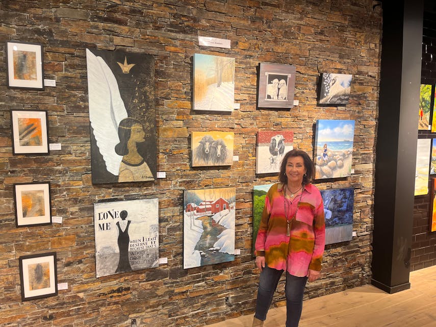 Mette Tuen Bakken og hennes malerier i bakgrunn. Hun er glad i å male bilder av dyr og livlig natur.