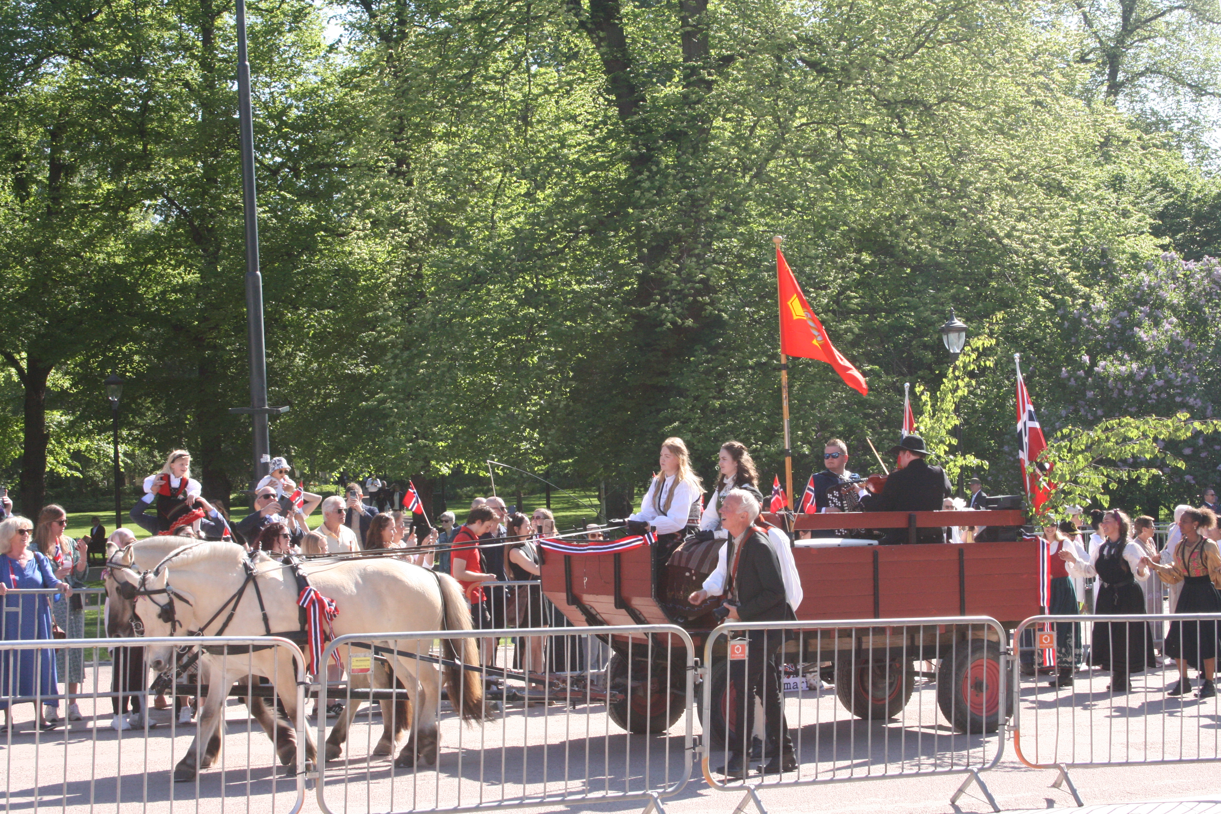 VARMET OPP PUBLIKUM: Før barnetoget startet, fikk publikum varme opp da hest og kjerre med folkedansere etter seg tok turen nedover.