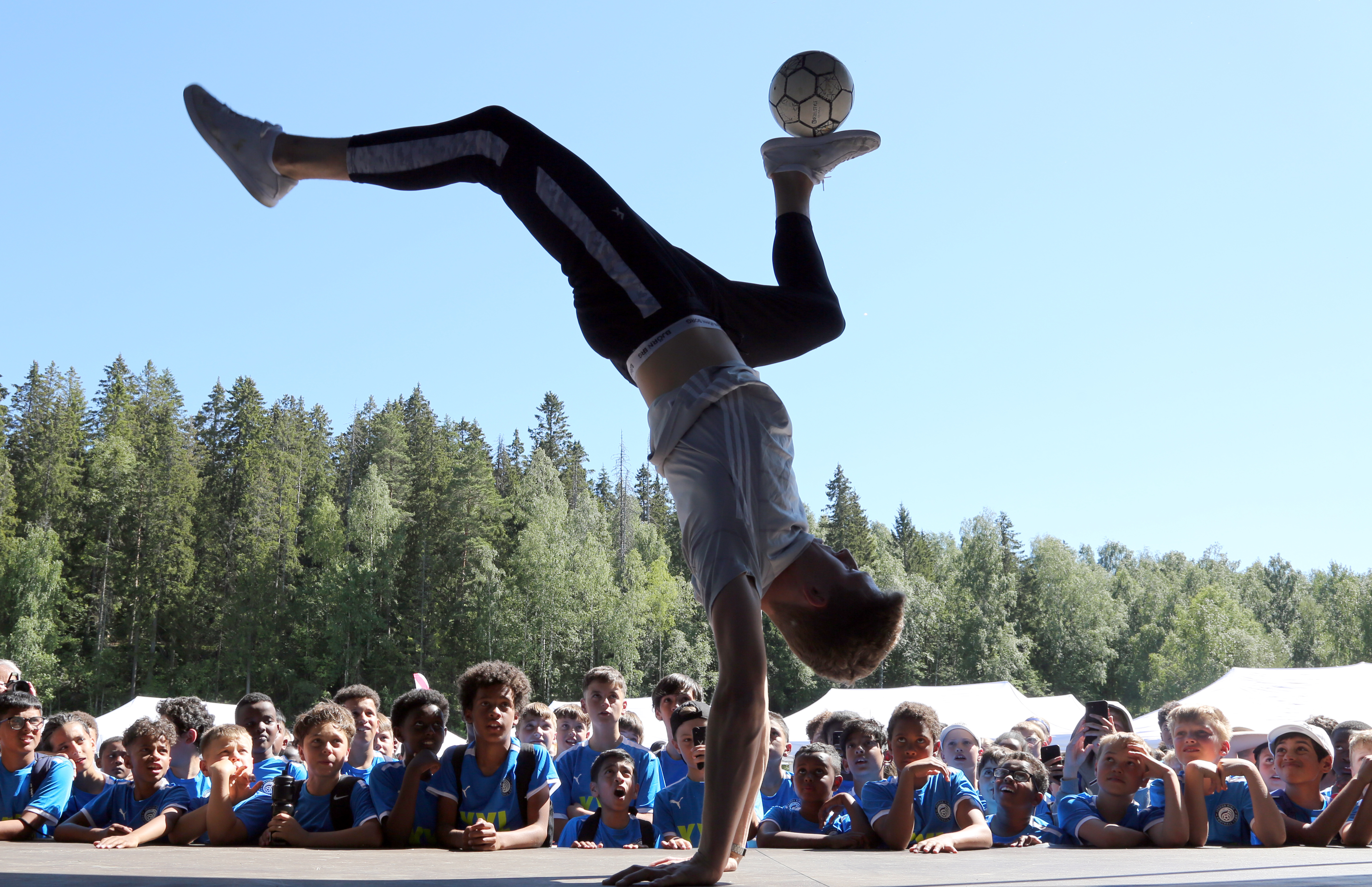 IMPONERENDE TEKNIKK: Én ting er å trikse en ball stående på beina, stående baklengs på henda, derimot! Men Robert Gomola kan kunsten og forbløffet fotballskoledeltakerne under åpningen av Joshua Kings fotballskole.