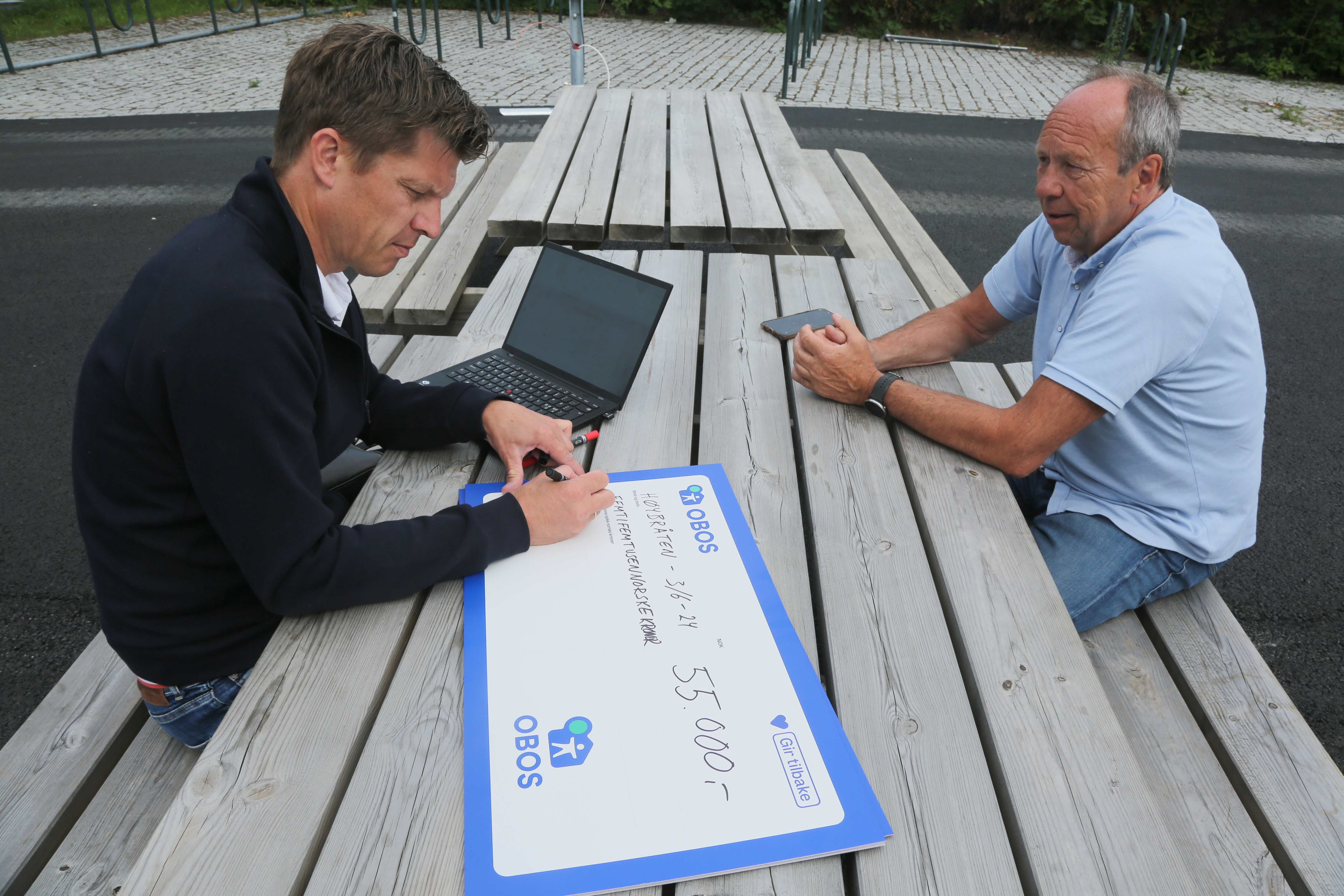 SKRIVEGLAD SPONSORSJEF: Rasmus Aarflot skriver ut en sjekk på kroner 55.000 til styreleder Jon Schmidt i Høybråten og Stovner IL.