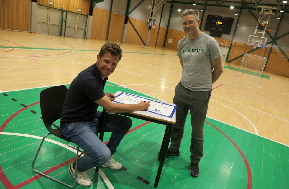 I HALLEN: Sponsorsjef Rasmus Aarflot signerer sjekken pålydende kroner 75.000 i Apalløkka flerbrukshall som skal gå til å arrangere åpen hall i sommer. En takknemlig styreleder Jo Andreas Fagerheim i Ammerud Basket følger med.