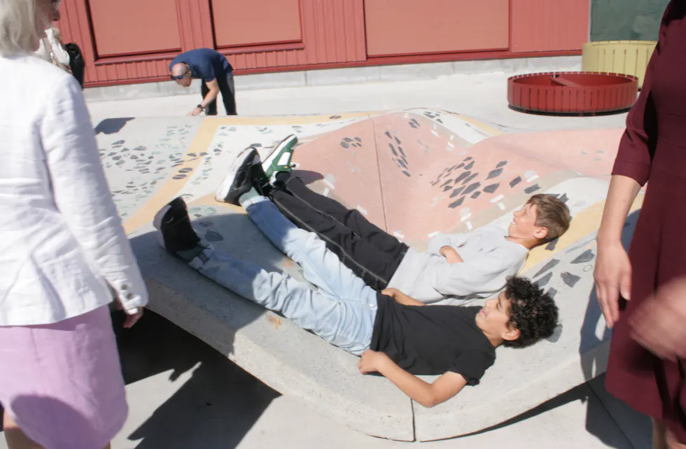 MED BEINA HØYT: Yosef og Marius viste gjestene rundt på sin nye skole. Dette kunstverket av et flyvende teppe er det perfekte sted å slenge seg ned litt, beviste de.