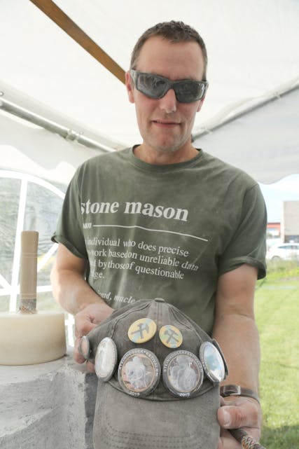 IVRIG DELTAKER: Andrew Smith har vært med på hver eneste steinhoggerfestival. På capsen sin har han seks buttons som hver viser bilder av de kunstverkene han har laget. Han kan forsikre at han har plass til den han skal lage i forbindelse med årets festival også.