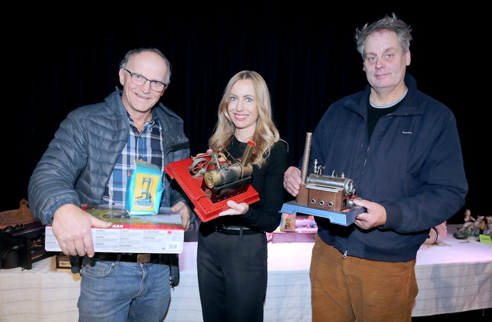 HARD KAMP: Jørn Slette (t v) og Karsten Pedersen kjempet lenge om denne dampmaskinmodellen fra 1950-tallet. Kelly Lillesund som viste fram auksjonsobjektene synes det var bra med budkamp - det gir mer penger til korpset.