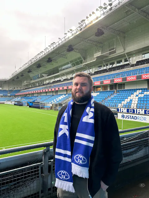 STORT KARRIEREHOPP: Thor Olav Tvedt Delgado-Rodriguez er klar for nye utfordringer som publikumsansvarlig i Molde FK, etter fem år med dedikert innsats for Haugerud IF. Her står han stolt på Aker stadion i sine nye farger. Foto Molde FK.