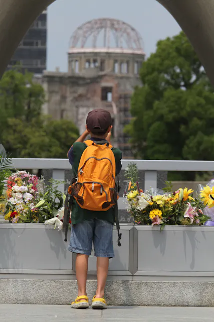 GODT SYNLIG : En liten japansk gutt tar bilde av Atombombe-kuppelen fra der han står ved marmor-buen i fredsparken i Hiroshima.