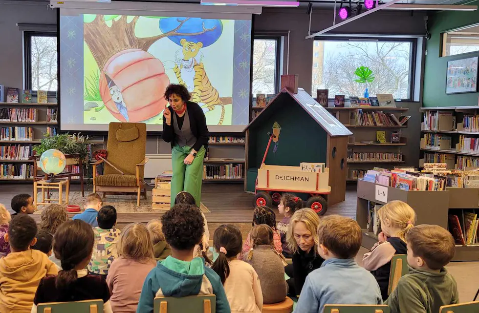 FEIRET SPRÅK: Barn og voksne samlet seg på Deichman Nordtvet for å feire morsmålsdagen med fortellinger, dikt og sanger på flere språk. Her med Parichehr Taheri på scenen foran engasjerte barn.