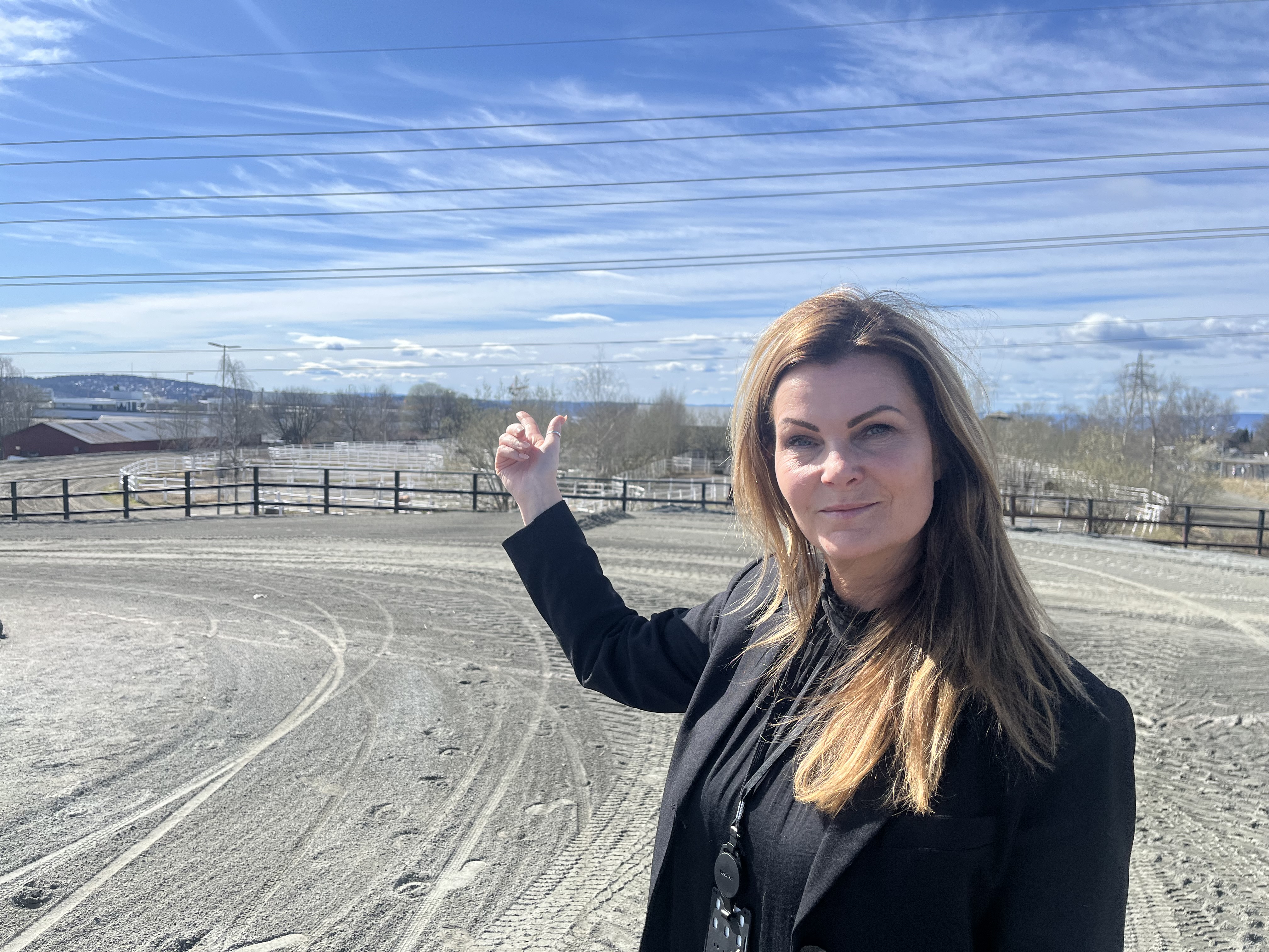 GLEDER SEG: Daglig leder i Bjerke Travbane Eiendom, Kathrine Nyhus, peker ut over området som skal kalles «Parkbyen», hvor hundrevis av nye boliger skal vokse fram og erstatte stallene.