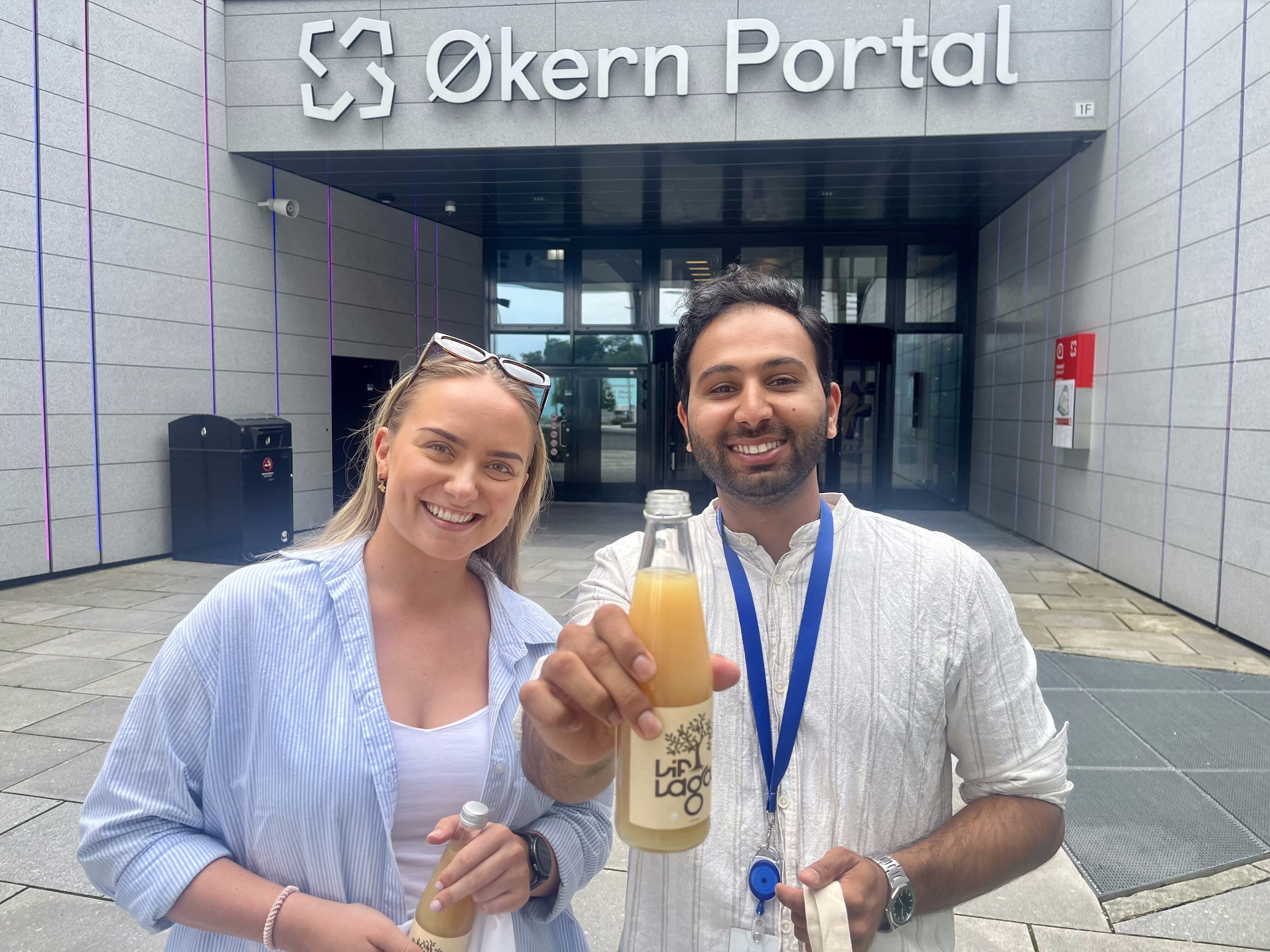 STJERNEDUO: Cecilie Sørli og Hussein Amad tok imot lokal eplemost fra Lif Laga med et smil. Den kommer godt med når de skal holde koken gjennom uker med lav bemanning på kontoret. Her står de foran Økern Portal, hvor Sparebank1 Østlandet deler bygg med blant andre Telia og DNB.