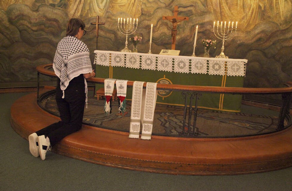 ORD OG SYMBOLER: Prest Tone Marie Falch i bønn for det palestinske folket, mens symboler til støtte for Gaza henger på alterringen.