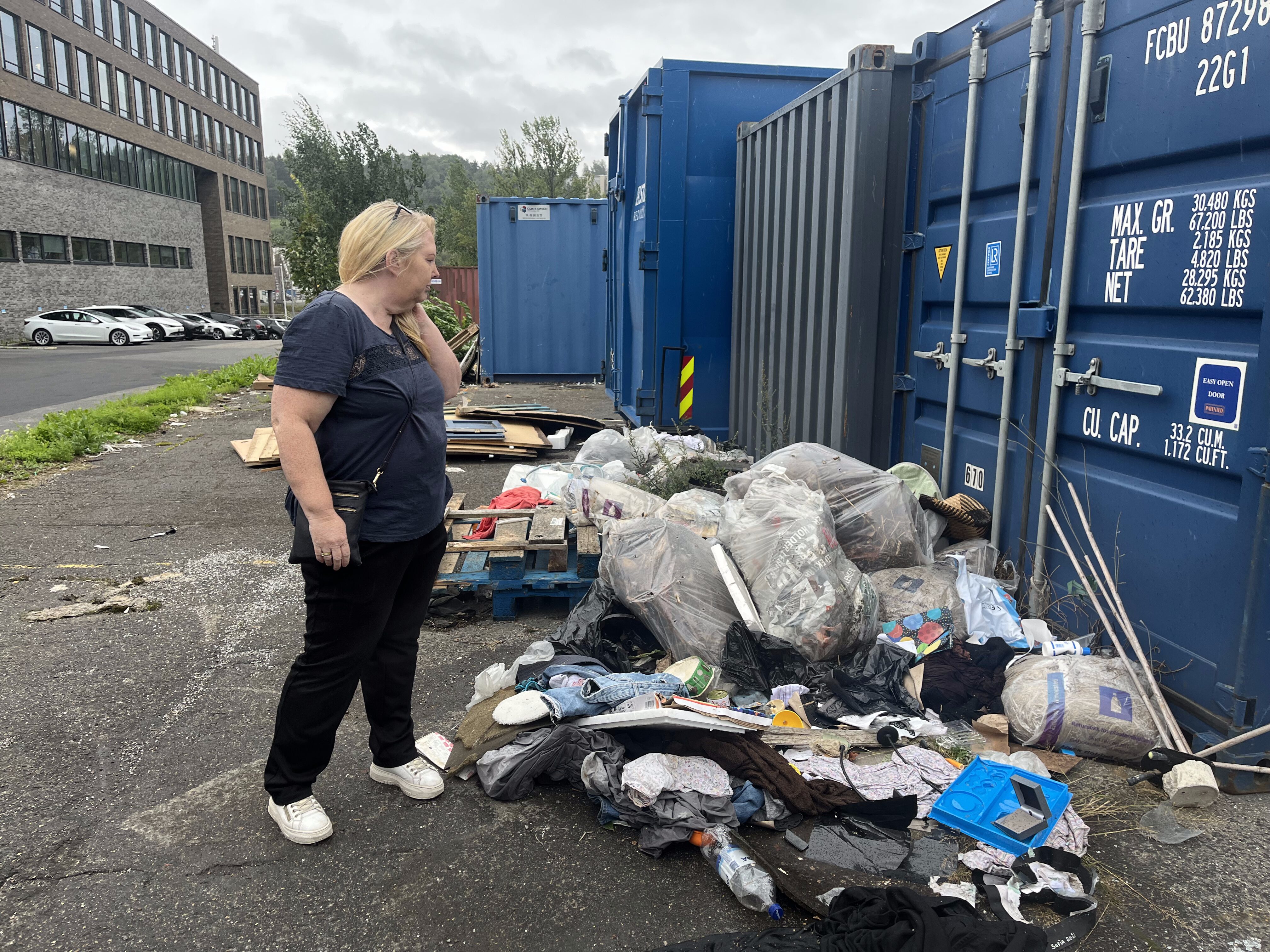 OPPGITT: Trude Larsen viser fram søppelhaugene bak containerne ved Skousen Alna. – Dette må vi få slutt på, sier hun.