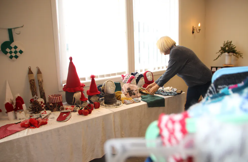 SISTE FINPUSS: Anne-Cathrine Holmesland gjør klar salgsbordet med strikk, luer og julepynt før helgens basar i Huset Vårt på Høybråten.