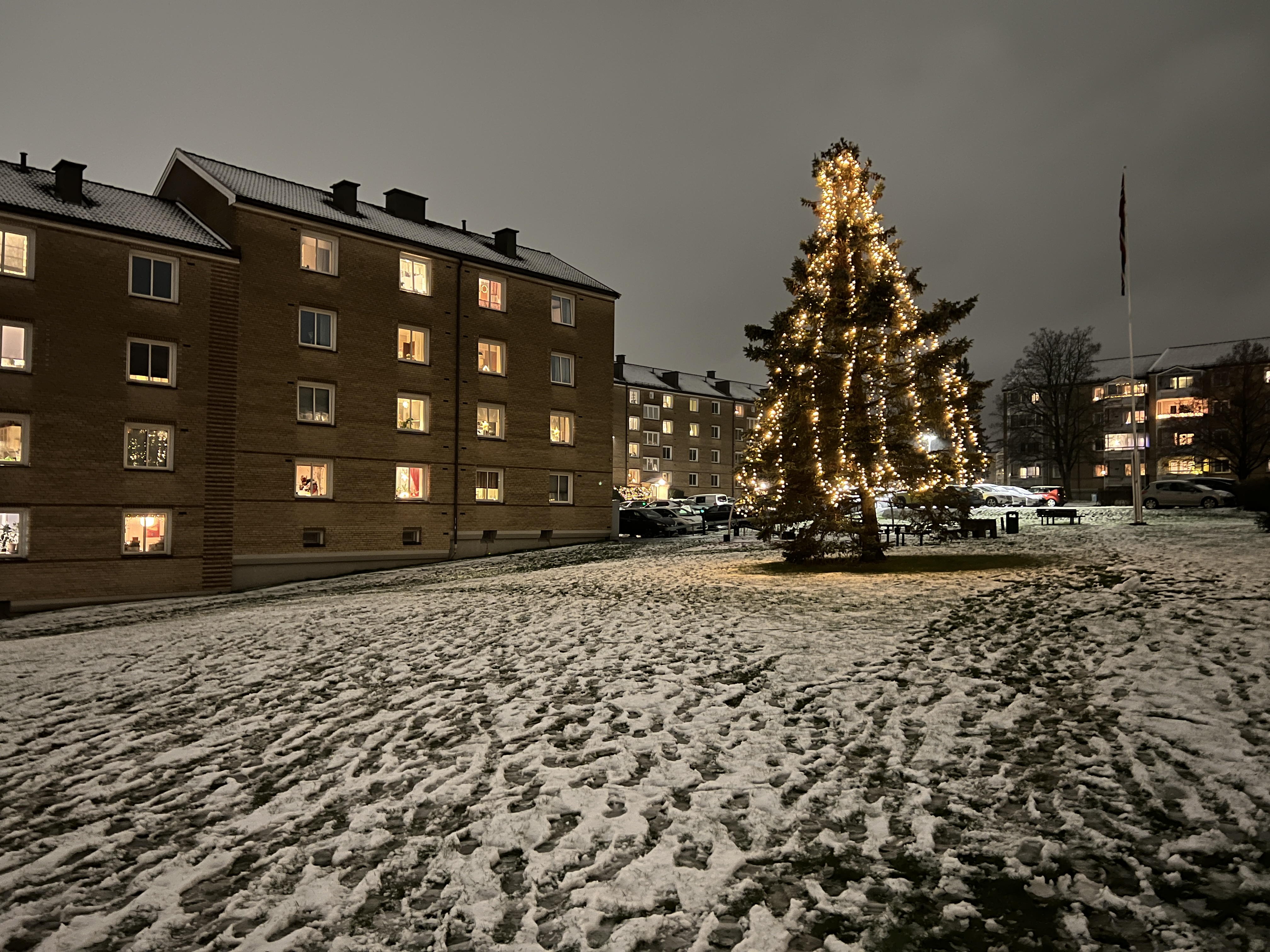 AKERLI BORETTSLAG GLIMTER I ADVENTSMØRKET: Julegrana på tunet i Akerli borettslag sprer varme over snøen, mens lysene fra leilighetene rammer inn stemningen. (Foto: Tom Evensen)