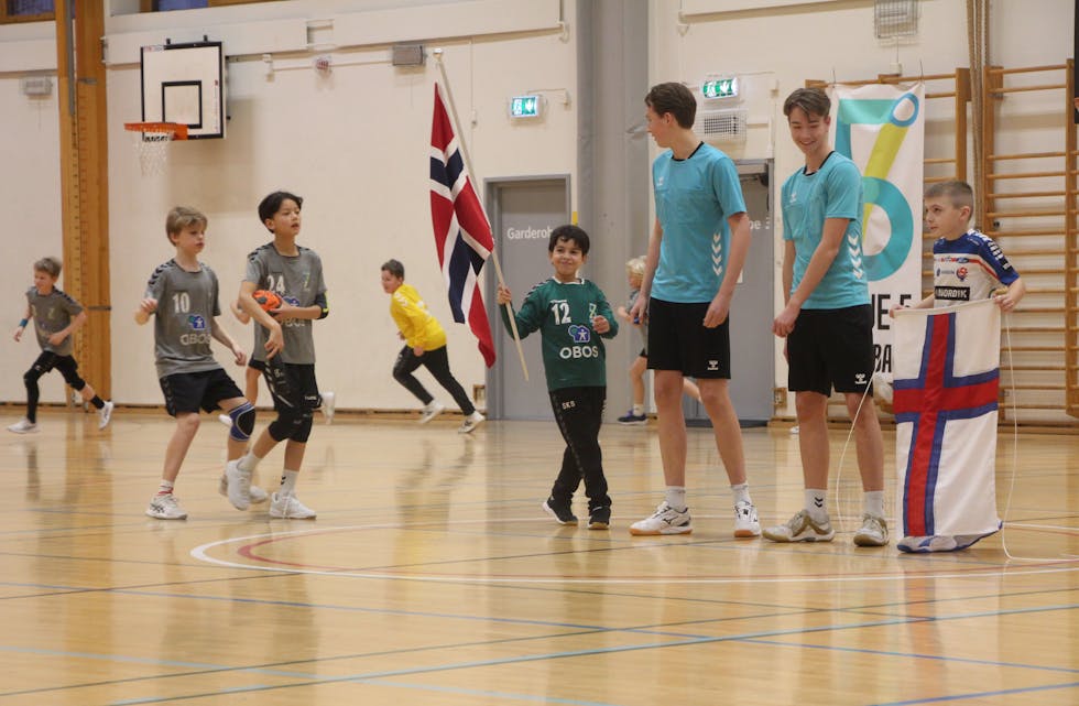 MINI-EM: Spillere fra Linje 5 og H71 samlet på banen i Linderudhallen før avkast, klare for uoffisiell landskamp mellom Norge og Færøyene med flagg, innmarsj og solid støtte fra tribunen.