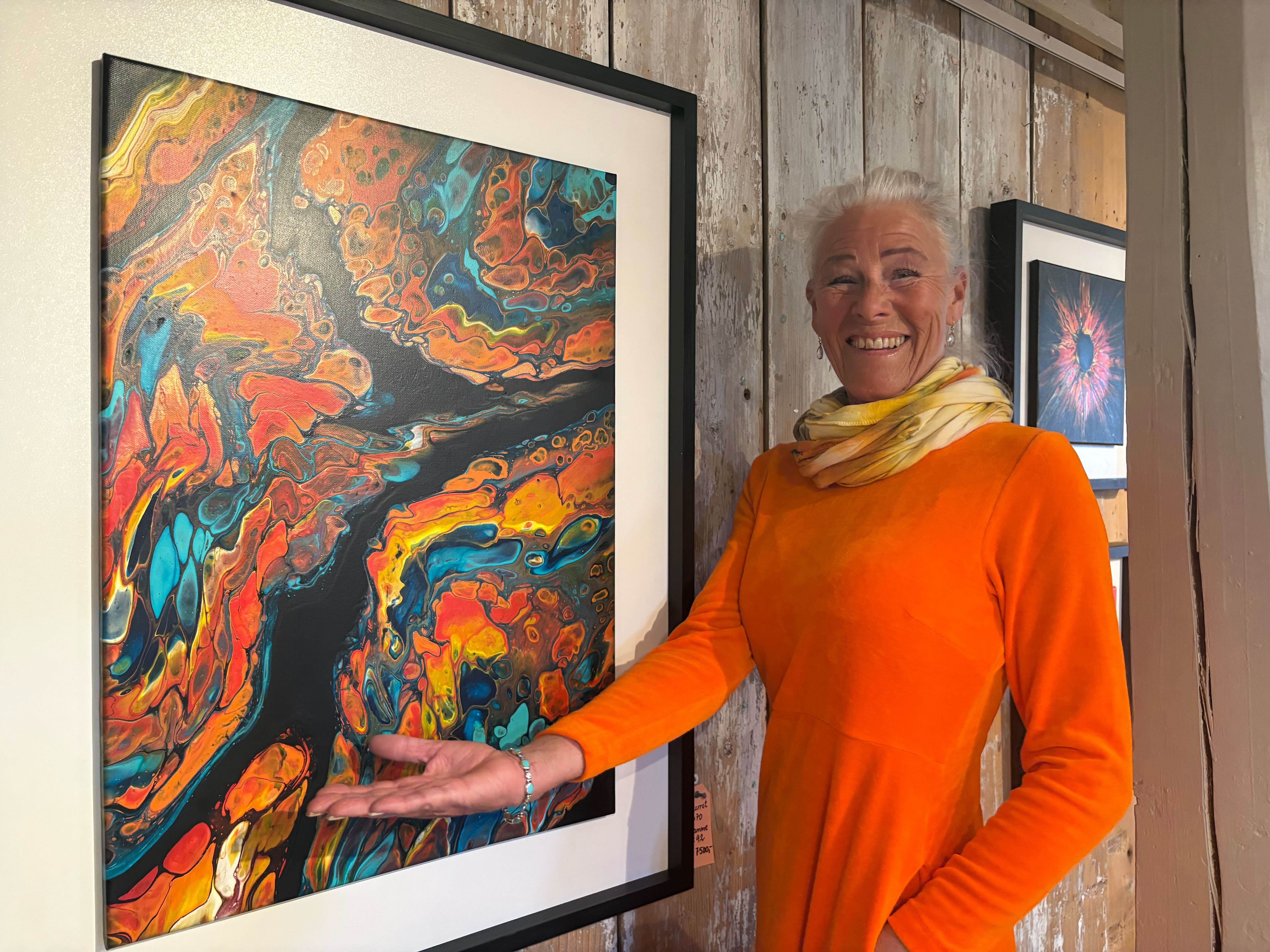 STOR RESPONS: Runa-Helene Larsson viser frem ett av sine fargerike, abstrakte verk under debututstillingen «Feire livet» på Årvoll gård.