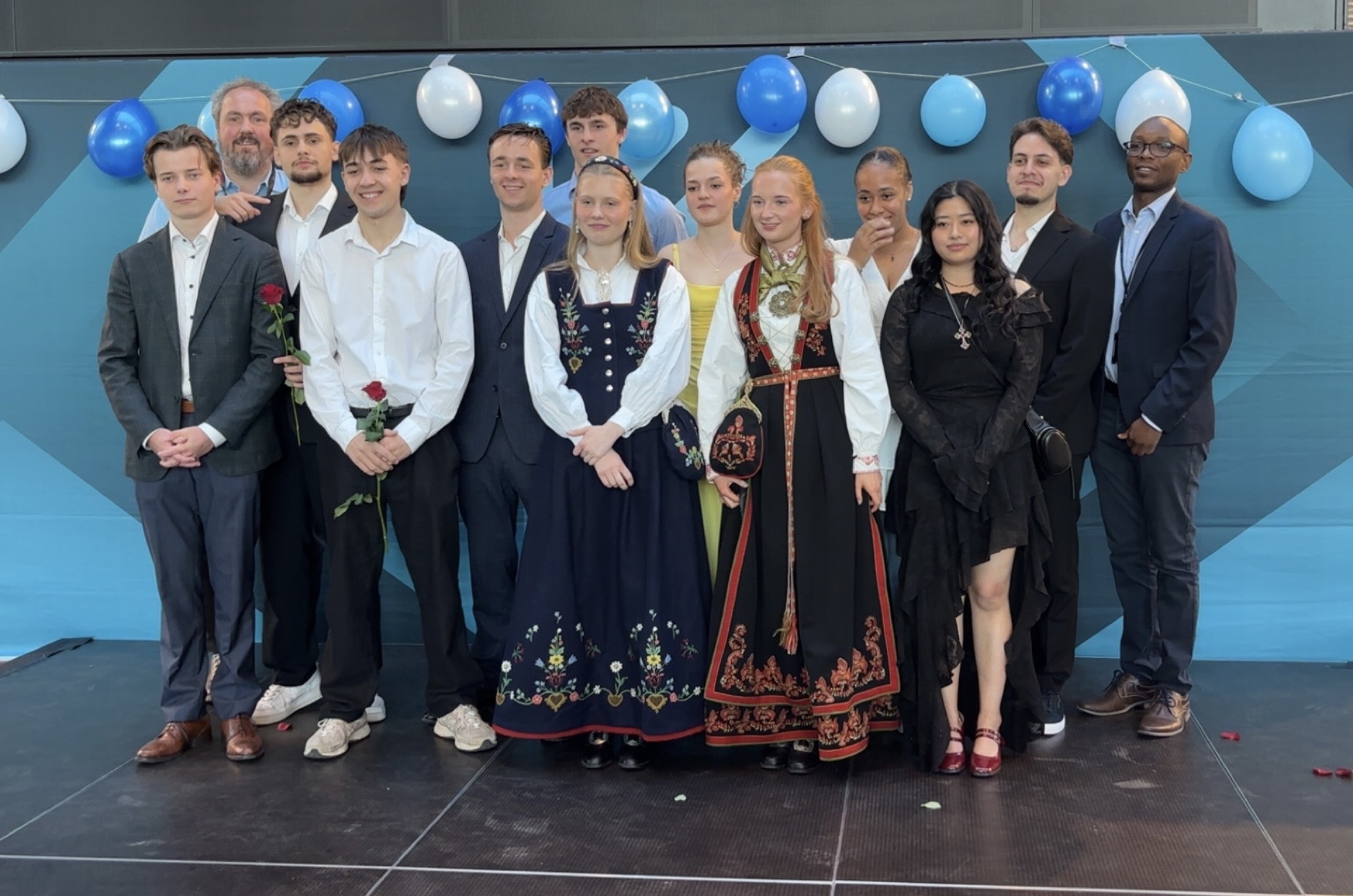 FERDIGE PÅ KUBEN: Avgangselevene fra BYSK og HYSK – yrkes- og studiekompetanse innen byggfag og helsefag – samlet seg foran skolens populære fotovegg etter avslutningsseremonien.