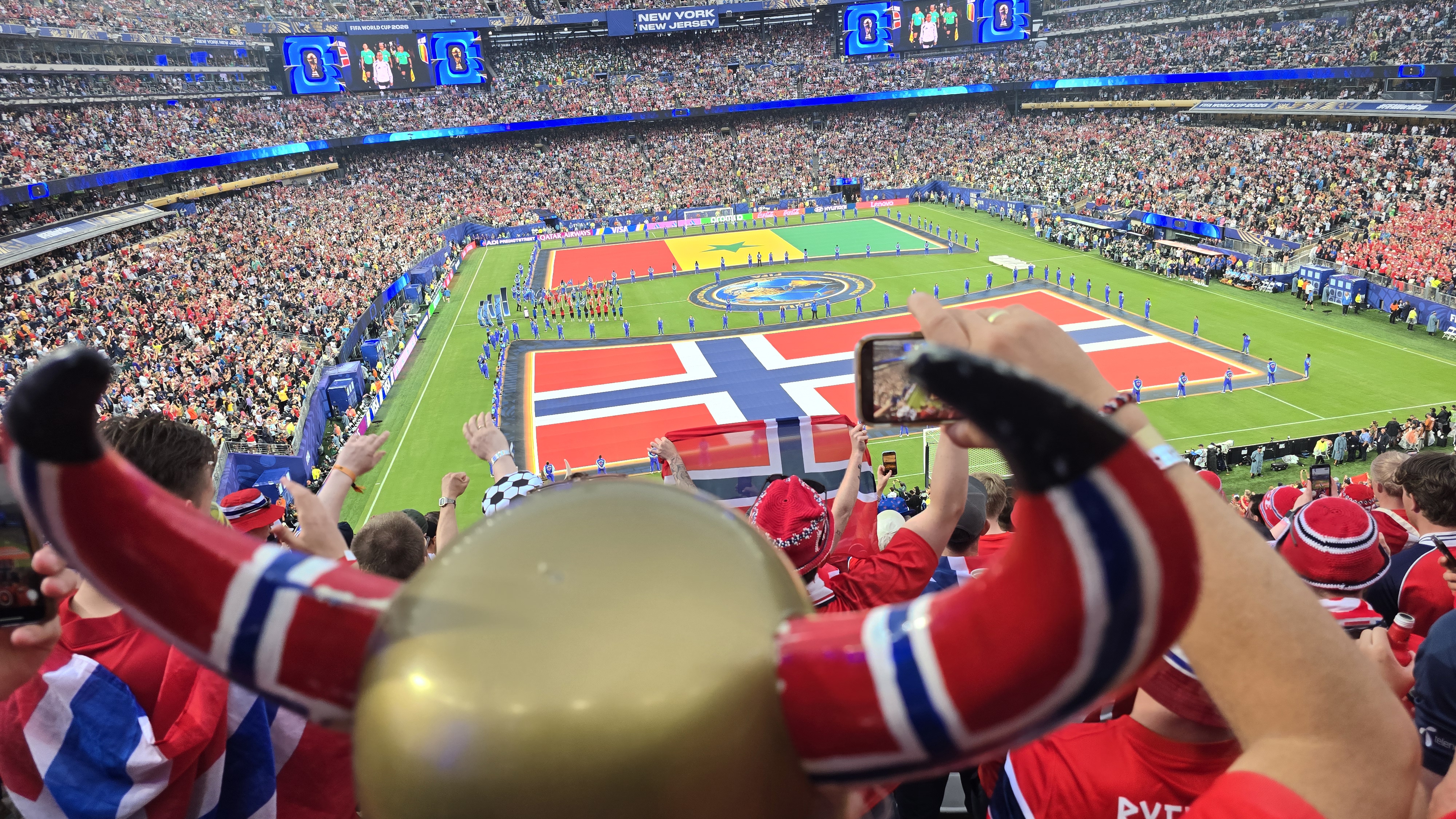 PÅ TRIBUNEN: Norske supportere farger New York New Jersey Stadium rødt, hvitt og blått før avspark mot Senegal. Kåre Ruud og Jarle Grøstad beskriver stemningen som elektrisk da flere tusen nordmenn samlet seg til VM-fest.