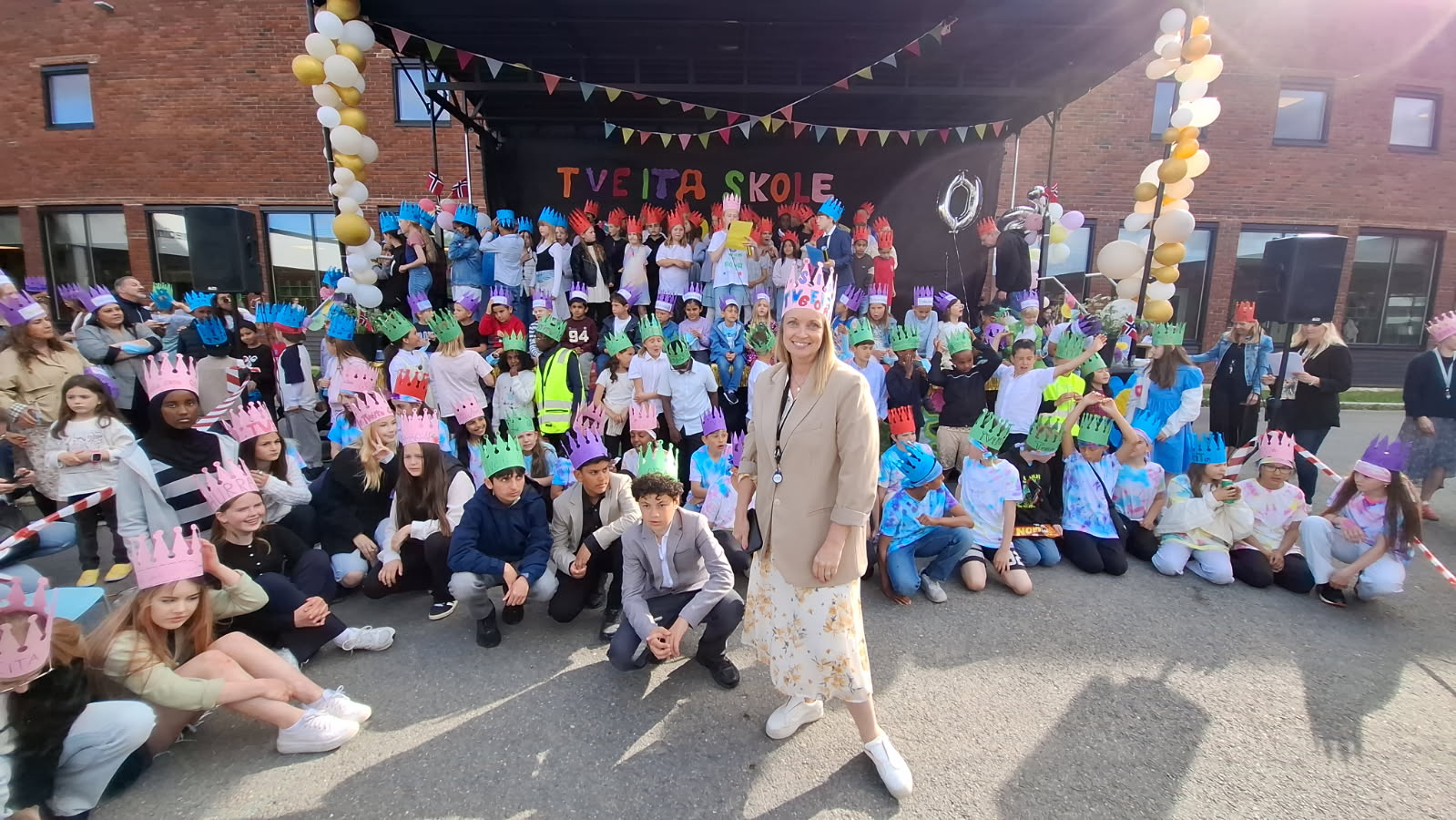 JUBILEUMSFEST: Elever fra hele Tveita skole samlet seg på jubileumsscenen sammen med rektor Siw Anita Johnsen under markeringen av skolens 60-årsdag. Fargerike bursdagskroner og stor jubel satte stemningen for feiringen.