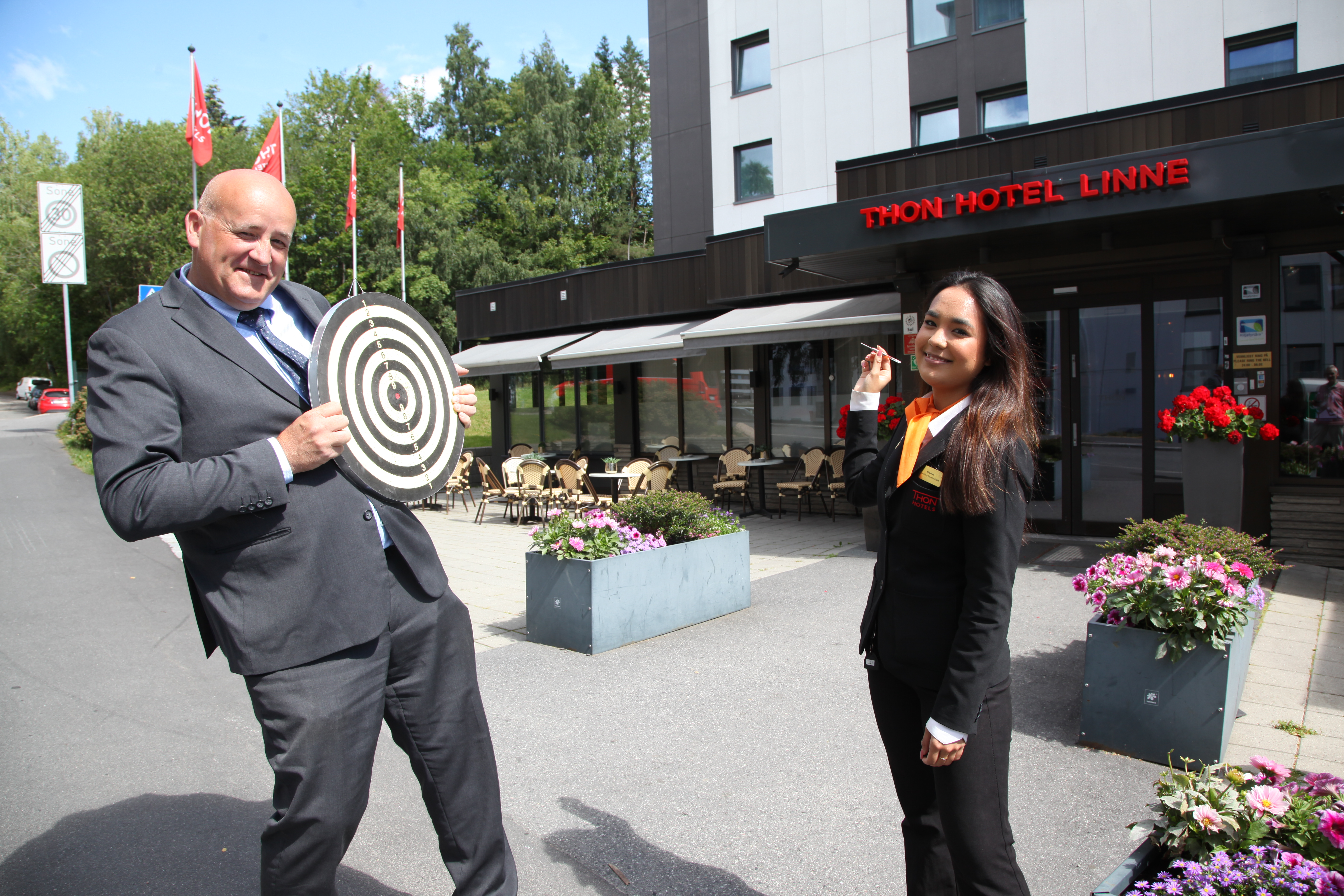 FARLIG MANØVER: Nyutdannet hotellærling Elisabeth Kolve og hotelldirektør Are Gald ved Thon Hotel Linne ønsker velkommen til årets sommerdart på hotellet under Norway Cup-uka. Da skal hotelldirektøren slippe å stå som «levende blink» – men det vil alltid være om å gjøre å treffe blinken.