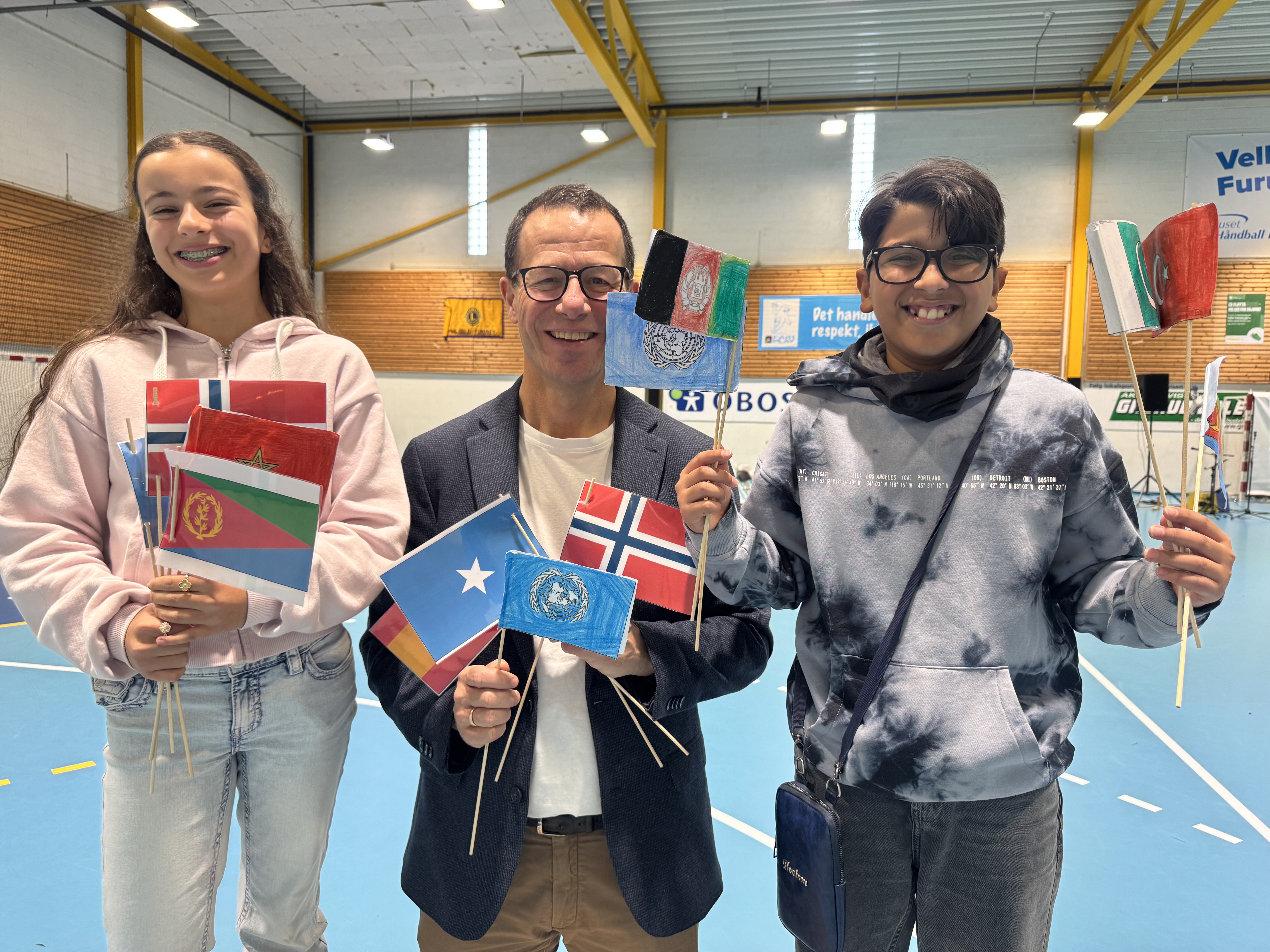 STOLTE AV FURUSET: Selma (11) og Malik (10) fra sjette klasse sammen med rektor Nils Otto Steen-Utheim. Med flagg fra ulike land markerte de FN-dagen og Furusets historiske tilknytning til FNs første generalsekretær, Trygve Lie.